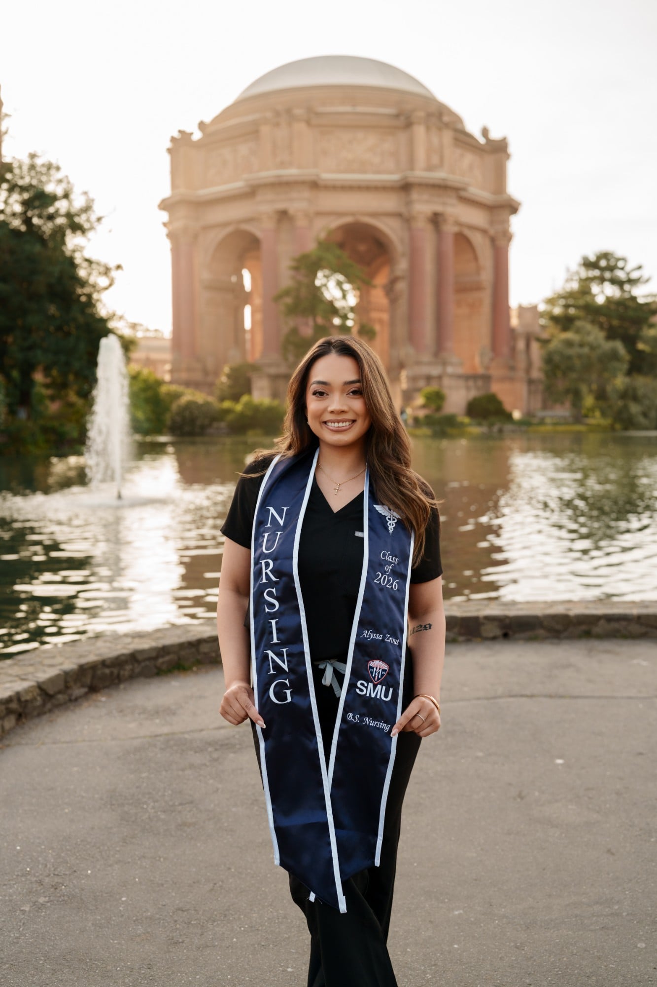 Nursing grad in black scrubs wearing SMU Nursing Class of 2026 stole standing in front of Palace of Fine Arts rotunda