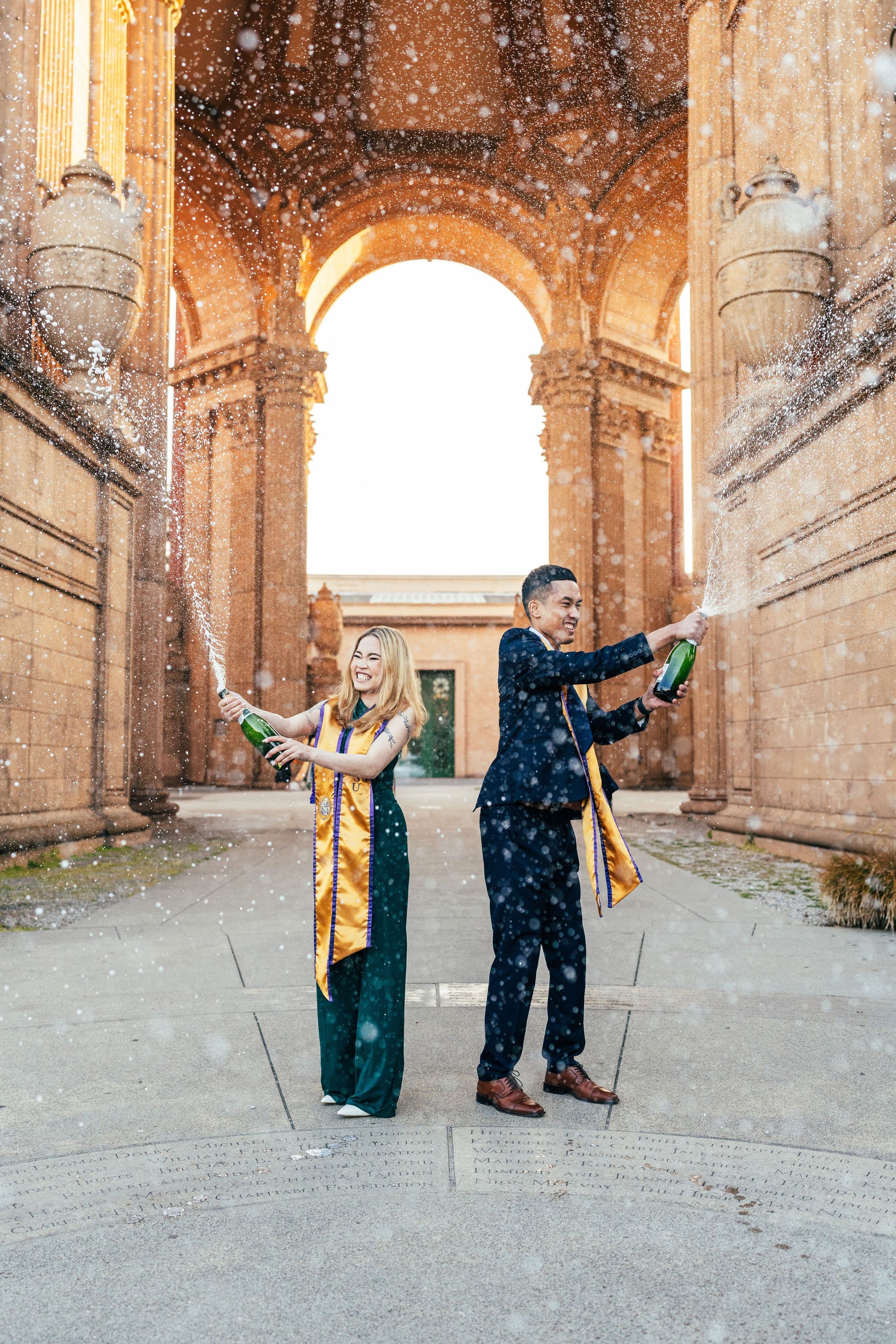 SF State graduate posing in cap and gown at the Palace of Fine Arts in San Francisco during golden hour