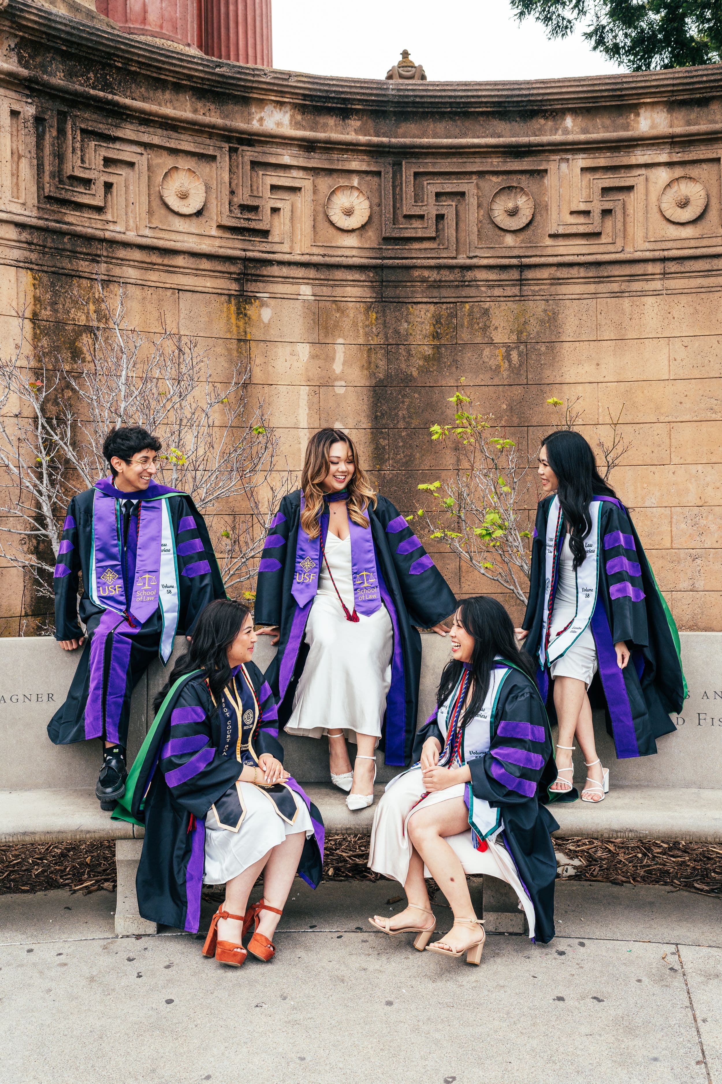 UC Law graduate posing in cap and gown at Palace of Fine Arts in San Francisco during golden hour